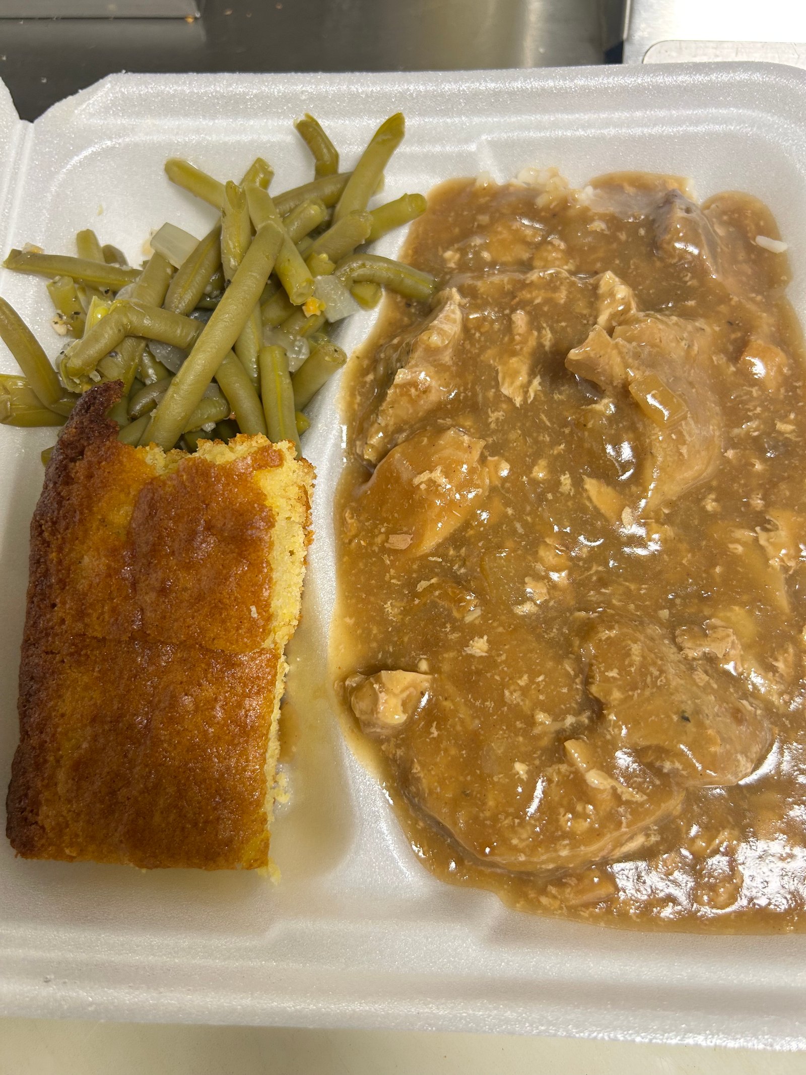 Smothered chicken with gravy, green beans and cornbread